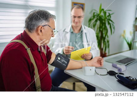 Doctor checks blood pressure of patient in modern clinic setting Doctor checks blood pressure of patient in modern clinic setting 132547112