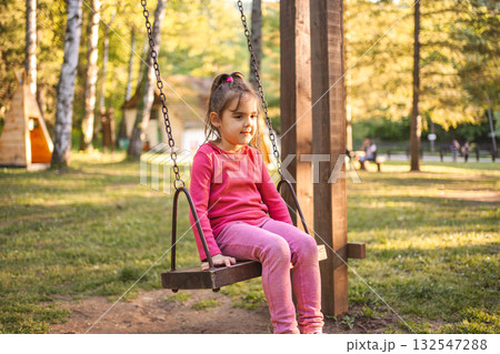 Cute smiling girl on a swing in the playground Cute smiling girl on a swing in the playground 132547288