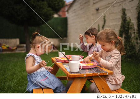 Joyful afternoon of children enjoying snacks in a sunny garden 132547293
