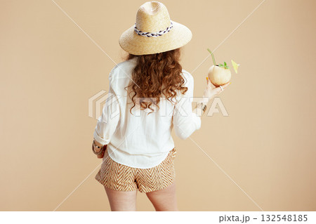 Seen from behind woman in blouse and shorts on beige Seen from behind woman in blouse and shorts on beige 132548185
