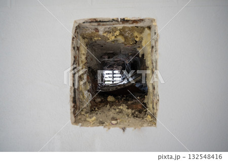 Closeup of neglected old ventilation hole in the wall of a house, covered with dust and cobwebs 132548416