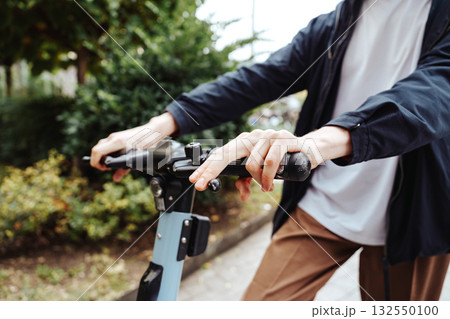 Person riding an electric scooter on a city sidewalk during daytime 132550100