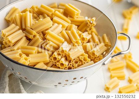 Cinque buchi. Uncooked italian pasta in colander on white table. Cinque buchi. Uncooked italian pasta in colander on white table. 132550232