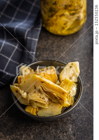 Pickled artichoke in bowl on black table. Pickled artichoke in bowl on black table. 132550236