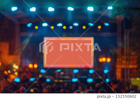 Blurred concert stage with glowing screen and bright lights, creating dynamic atmosphere with copy space for text or branding. Concept of live show, digital display, event 132550602