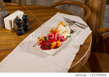 A Vibrant and Colorful Fresh Fruit Platter on a Beautiful Wooden Table Setting that exudes charm 132550698