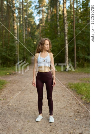 Fitness Enthusiast in Nature Standing Strong Amongst the Trees and Embracing the Outdoors Fitness Enthusiast in Nature Standing Strong Amongst the Trees and Embracing the Outdoors 132550789