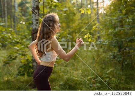 An Active Woman Engaging in Jogging Within a Beautiful and Lush Forest Environment 132550842