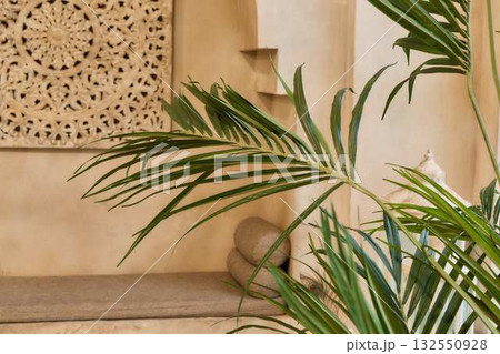 Sunlit Boho Interior with Carved Wall Decor and Tropical Palm - Serene Minimal Spa Setting Sunlit Boho Interior with Carved Wall Decor and Tropical Palm - Serene Minimal Spa Setting 132550928