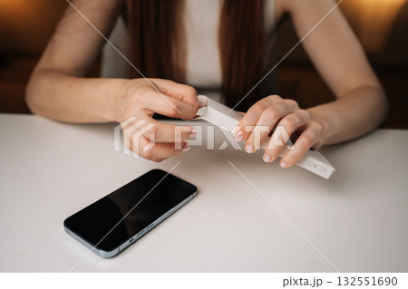 Cropped shot of woman opening white retail box containing new phone cable adapter, holding over clean white table with smartphone positioned nearby, showcasing excitement and anticipation. Cropped shot of woman opening white retail box containing new phone cable adapter, holding over clean white table with smartphone positioned nearby, showcasing excitement and anticipation. 132551690