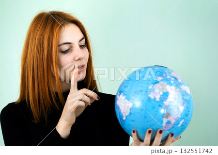 Portrait of a happy young woman holding geographic globe of the world in her hands. Travel destination and planet protection concept. 132551742