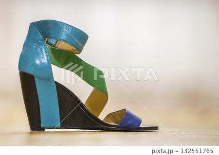 One colorful bright blue, green and yellow leather strap female shoe sandal on high black platform isolated on light copy space background. Style and fashion, modern comfortable footwear for summer. One colorful bright blue, green and yellow leather strap female shoe sandal on high black platform isolated on light copy space background. Style and fashion, modern comfortable footwear for summer. 132551765
