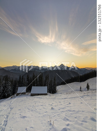 Old wooden house, hut and barn in deep snow on mountain valley, spruce forest, woody hills on clear blue sky at sunrise copy space background. Mountain winter panorama landscape. Old wooden house, hut and barn in deep snow on mountain valley, spruce forest, woody hills on clear blue sky at sunrise copy space background. Mountain winter panorama landscape. 132551766