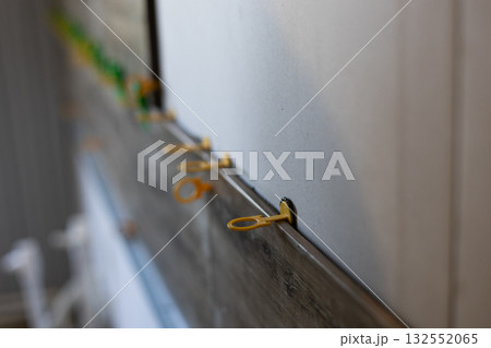Applying yellow tile leveling clips between new floor tiles and a wall to ensure an even, flat surface during home renovation, close-up of precise tiling installation. 132552065