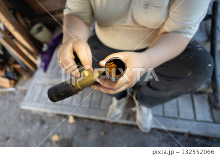A plumber holds a cross-section of a water pipe, revealing severe internal corrosion and rust deposits. The condition of the old pipe indicates problems and damage to the plumbing system. A plumber holds a cross-section of a water pipe, revealing severe internal corrosion and rust deposits. The condition of the old pipe indicates problems and damage to the plumbing system. 132552066