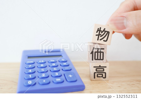 物価高をイメージした木のブロックと青い電卓。コピースペースあり。 132552311