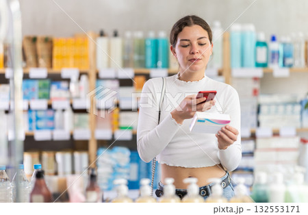 Girl scans code on package of pills to check expiration date Girl scans code on package of pills to check expiration date 132553171