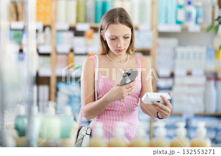 Girl in summer clothes scans code on package of pills to check expiration date 132553271