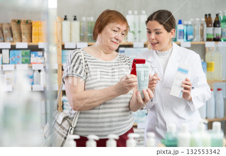 Woman buyer scans cream qr code with woman pharmacist 132553342