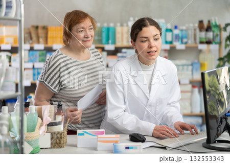 Female pharmacist counseling mature woman near cash register in pharmacy 132553343