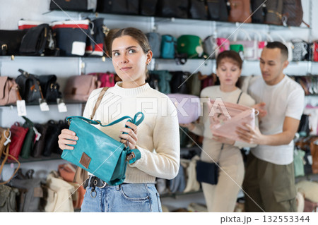 Young woman choosing handbag in store Young woman choosing handbag in store 132553344