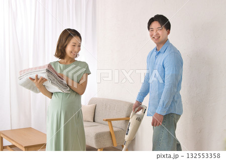 妊婦の女性と楽しそうに話しながら掃除機をかける若い男性 妊婦の女性と楽しそうに話しながら掃除機をかける若い男性 132553358