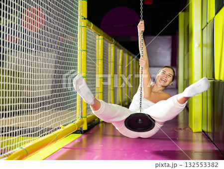 Happy girl goes down zip line at high speed in an amusement park. Storm of emotions and delight Happy girl goes down zip line at high speed in an amusement park. Storm of emotions and delight 132553382