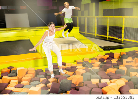Cheerful girl jumping in foam pit at trampoline park 132553383