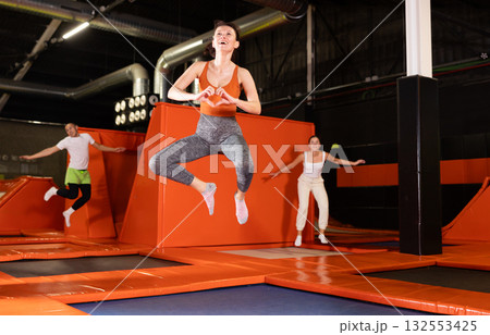 Cheerful woman jumping at modern colorful trampoline park Cheerful woman jumping at modern colorful trampoline park 132553425