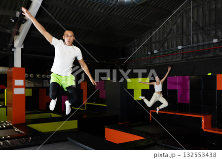 Cheerful young man jumping in modern indoor trampoline park Cheerful young man jumping in modern indoor trampoline park 132553438