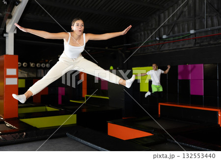 Cheerful young girl jumping in indoor trampoline arena Cheerful young girl jumping in indoor trampoline arena 132553440
