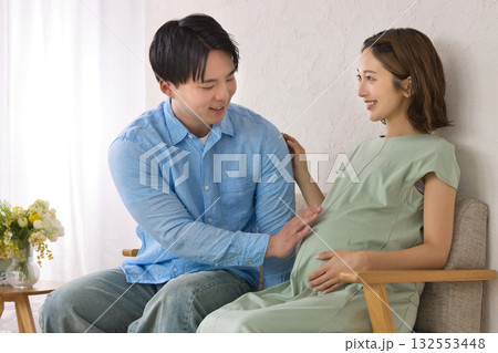 ソファに座ってくつろぐ若い夫婦　妊婦さん 132553448