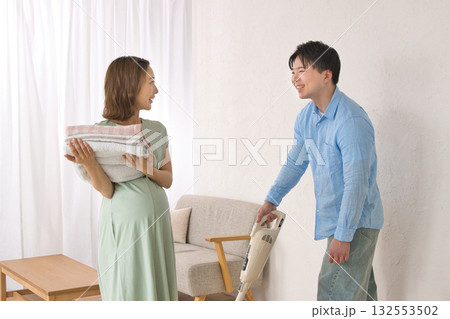 妊婦の女性と楽しそうに話しながら掃除機をかける若い男性 132553502