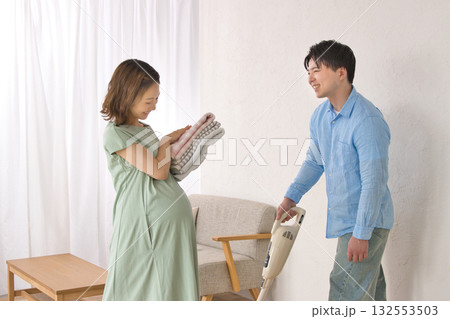 妊婦の女性と楽しそうに話しながら掃除機をかける若い男性 妊婦の女性と楽しそうに話しながら掃除機をかける若い男性 132553503