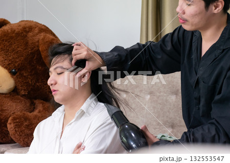 Two Thai LGBTQ friends share a warm moment as one helps dry the others hair at home expressing care friendship and calm lifestyle connection Two Thai LGBTQ friends share a warm moment as one helps dry the others hair at home expressing care friendship and calm lifestyle connection 132553547