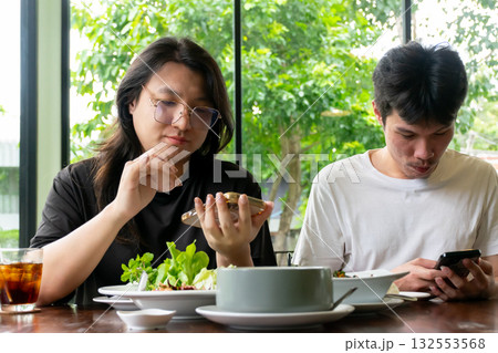 Two Thai LGBTQ friends enjoying lunch together scrolling through phones sharing moments online in cozy daylight cafe showing friendship connection and real lifestyle happiness Two Thai LGBTQ friends enjoying lunch together scrolling through phones sharing moments online in cozy daylight cafe showing friendship connection and real lifestyle happiness 132553568