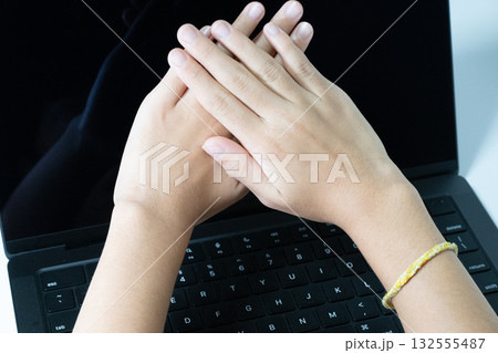 ノートパソコン上で手を重ねる女性 132555487