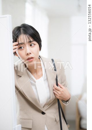出勤前に身だしなみを確認するスーツの女性 時間がない忙しい朝 出勤前に身だしなみを確認するスーツの女性 時間がない忙しい朝 132556054