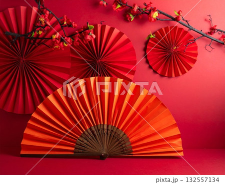 A traditional red Japanese folding fan opened with intricate paper patterns. A traditional red Japanese folding fan opened with intricate paper patterns. 132557134