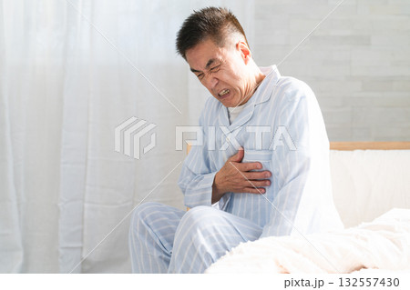 起きてベッドの上で胸を押さえている男性 起きてベッドの上で胸を押さえている男性 132557430