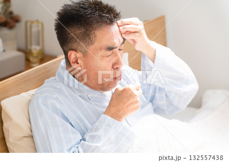 ベッドの上で咳き込む男性 132557438