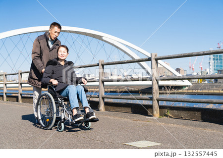 車椅子を押して散策する熟年夫婦 車椅子を押して散策する熟年夫婦 132557445