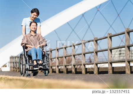 車椅子を押して散策する女性と介護士 車椅子を押して散策する女性と介護士 132557451
