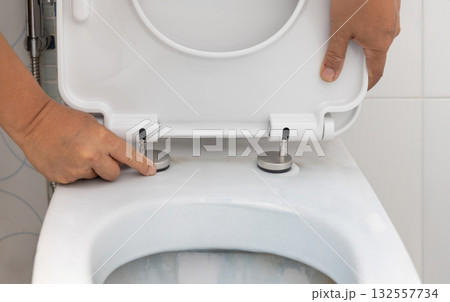 Handyman replace toilet seat cover. Bathroom toilet seat replacement concept. Handyman replace toilet seat cover. Bathroom toilet seat replacement concept. 132557734
