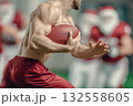 A muscular young Santa Claus is playing rugby with other santas. He runs with a rugby ball side view. Sports Christmas competitions. 132558605