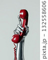 A silver-painted hand grips a vibrant red handset, illustrating the idea of communication and connection in a creative and artistic manner. This artwork represents customer service calls. 132558606