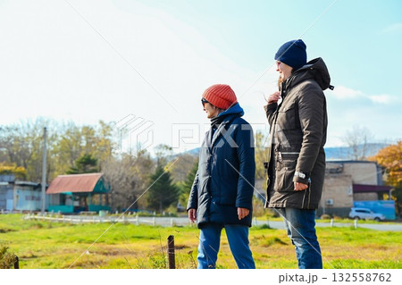 Two Russian women friends standing outdoors in Vladivostok, dressed warmly in jackets and hats, enjoying conversation on a cool autumn or spring day. Two Russian women friends standing outdoors in Vladivostok, dressed warmly in jackets and hats, enjoying conversation on a cool autumn or spring day. 132558762
