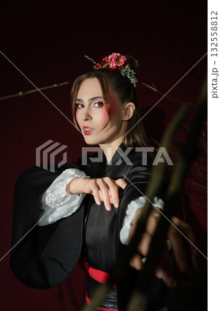 A woman dressed in a traditional Japanese outfit stands elegantly in a studio 132558812