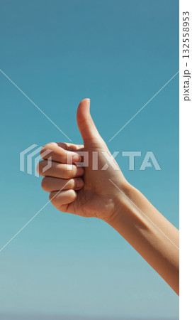 Thumbs up hand gesture against clear blue sky, positive approval, encouragement, cheerful mood 132558953