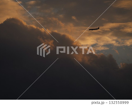 美しい夕焼けの空を飛ぶ飛行機 132558999